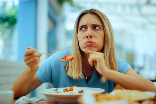 Woman Eating a Greek Salad Thinking About Mediterranean Diet. Lady thinking about eating healthy and appetizing foods in a diner
