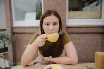 Young asian woman enjoys a cup of hot coffee in front of a cafe in Edinburgh, Scotland. people and lifestyles.