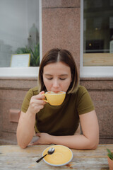 Young asian woman enjoys a cup of hot coffee in front of a cafe in Edinburgh, Scotland. people and lifestyles.