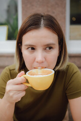 Young asian woman enjoys a cup of hot coffee in front of a cafe in Edinburgh, Scotland. people and lifestyles.