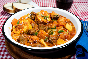 Delicious beef stew called carbonada with corn, potatoes, and carrots simmering in rich tomato sauce