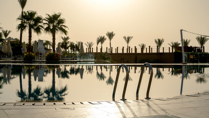 Swimming pool by the sea in the background of sunrise or sunset
