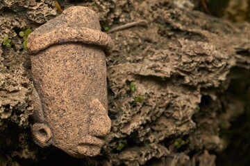 Fototapeta premium A close-up view of an ancient carved clay head partially buried in natural earthy surroundings, evoking archaeological and cultural heritage themes.