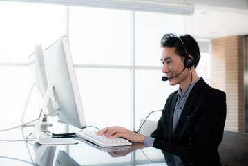 Smiling businessman wearing microphone headsets is working as customer care operator or help desk service call center office, provide product information to customer and Expedite debt collection.