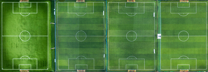 Aerial view of four vibrant green soccer fields, meticulously lined and ready for play, showcasing...