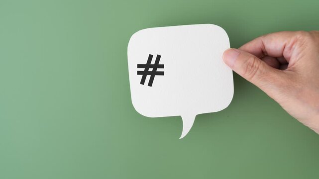 animated video of hand holding  white speech bubble with hashtag sign and couple red hearts on green background, health care,  valentine concept