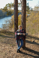 Portrait of smiling caucasian girl plays ukulele in autumnal park. Young woman plays guitar musical...