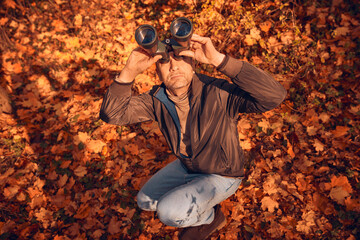 Amateur birdwatcher observing birds and other animals in nature with binoculars.