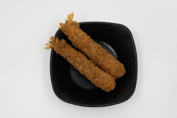 검은 접시에 담긴 바삭한 새우튀김 두 조각
