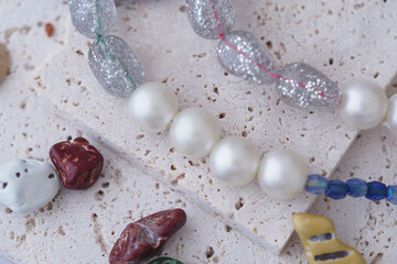 Colorful beads and pearls arranged on textured surface