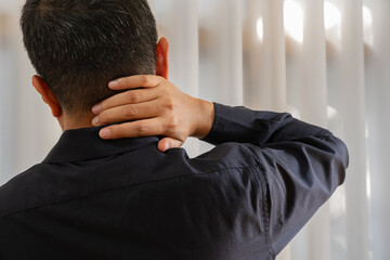 An Asian office worker experiences cervical discomfort, likely due to prolonged sitting and screen...