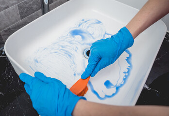 Young housewife diligently scrubs and cleans the sink in bathroom