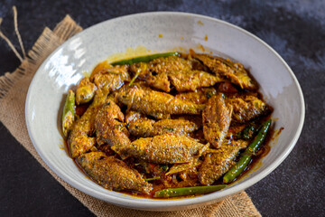Bengali-style puti fish jhal served in a bowl – spicy small fish curry, traditional Bengali non-veg dish, puti macher jhal, Indian freshwater fish in mustard gravy, homestyle overhead view
