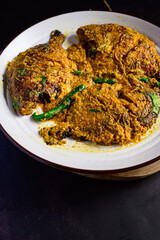 Pomfret jhal served in a plate – spicy Bengali pomfret curry, Indian fish in mustard and chili gravy, traditional seafood dish, homestyle non-veg meal, overhead view
