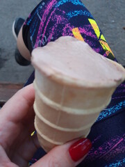 Hand holding ice cream on the background of legs in sportswear
