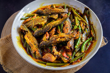 Traditional Bengali-style tangra fish curry cooked with onion flower stems (pyanjkoli) – tangra macher jhol with pyanjkoli, authentic Bengali fish dish, homestyle Indian fish curry, rustic comfort foo