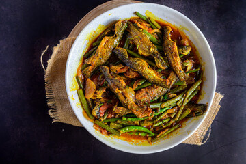 Traditional Bengali-style tangra fish curry cooked with onion flower stems (pyanjkoli) – tangra macher jhol with pyanjkoli, authentic Bengali fish dish, homestyle Indian fish curry, rustic comfort foo