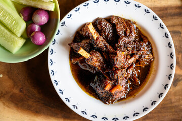 Traditional Bengali-style mutton kosha served in a small white bowl – spicy Indian goat curry, authentic Bengali kosha mangsho, slow-cooked meat dish, homestyle mutton curry, rustic overhead view