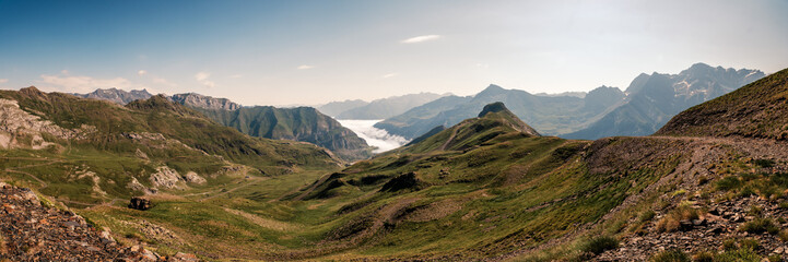 Panoramic view of the snow capped mountains of the French Pyrenees with mist hanging in the Gavarnie valley viewed from the Col de Tente