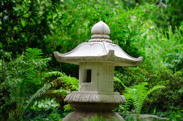 Stone lantern in a Japanese garden with ferns on the background
