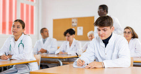 Doctors different age sitting at desk in classroom working during lesson at adult education class