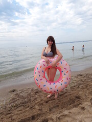 Woman near the sea with a large inflatable circle, shaped like a donut