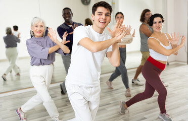 Fototapeta premium Smiling dark-haired young guy attending group choreography class, learning modern dynamic dances. Concept of active lifestyle ..