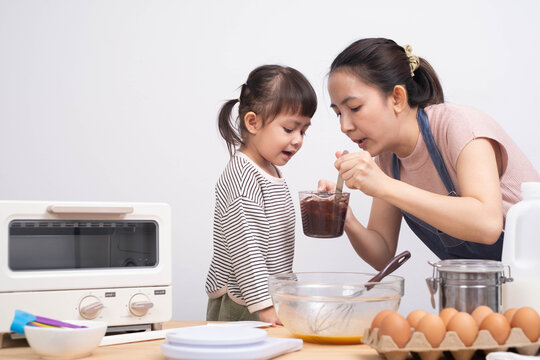 A mother and daughter joyfully engage in baking together, surrounded by various ingredients and kitchen tools.