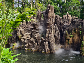 A beautiful waterfall is surrounded by numerous rocks and lush trees