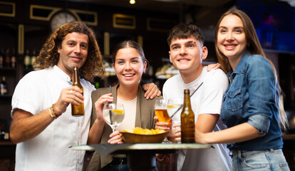 Portrait of happy friends in a beer bar chatting and drinking beer