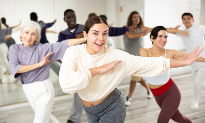 Portrait of cheerful young girl enjoying active dancing during group training in dance studio..