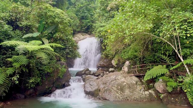 A stunning natural waterfall known as Curug Hordeng, located in Bogor, Indonesia, flows gracefully through a lush green forest
