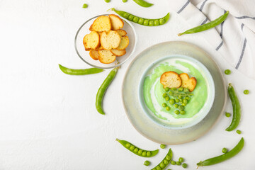 Green pea soup on a wooden table. Fresh pea soup bowl. Delicious healthy cream soup in a bowl with green peas and croutons. Healthy vegan puree. Copy space. Space for text.