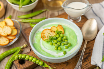 Green pea soup on a wooden table. Fresh pea soup bowl. Delicious healthy cream soup in a bowl with green peas and croutons. Healthy vegan puree. Copy space. Space for text.