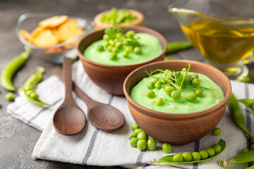 Green pea soup on a wooden table. Fresh pea soup bowl. Delicious healthy cream soup in a bowl with green peas and croutons. Healthy vegan puree. Copy space. Space for text.