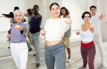 Positive determined young girl practicing basic punches during group self defense course ..