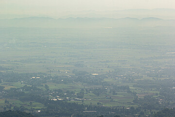 Aerial view of vast green landscape with distant hazy mountains, peaceful rural scenery and natural countryside atmosphere.