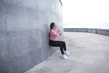 A sporty girl is dressed in sport clothes, leggins and rush guard doing sport exercises outside...