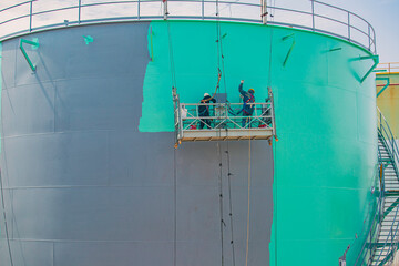 The male worker takes the cable car holding an industrial painting brush used for shell plate tank...