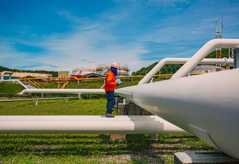 Male worker inspection at steel long pipes and pipe elbow in station oil factory during refinery valve of visual check record pipeline