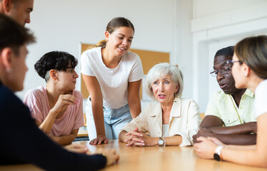 Adult students of different ages and teacher brainstorming round table in university classroom