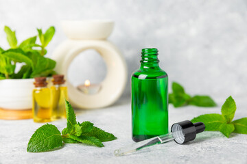 Essential oil mint on a wooden background. Peppermint essential oil with fresh mint leaves. A bottle of aromatherapy oil. Mint extract. The concept of natural cosmetics, spa care. copy space