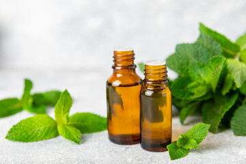 Essential oil mint on a wooden background. Peppermint essential oil with fresh mint leaves. A bottle of aromatherapy oil. Mint extract. The concept of natural cosmetics, spa care. copy space