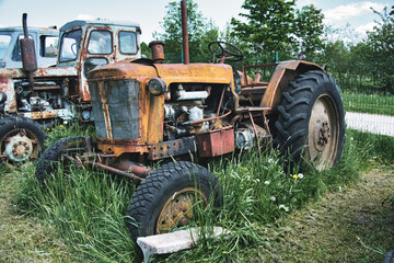 Obraz premium Rusty Vintage Tractors Abandoned in Overgrown Field