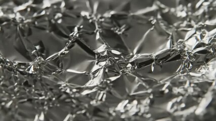 Close-up view of crumpled aluminum foil reflecting light, creating a textured and shiny surface - Powered by Adobe