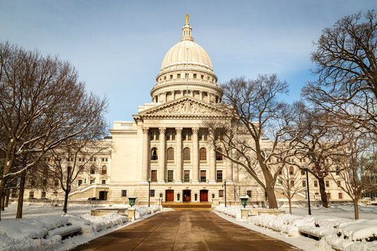 Fototapeta Wisconsin State Capitol in Madison, Wisconsin, captured during a bright winter day. The neoclassical architecture stands majestically, framed by leafless trees and fresh snow