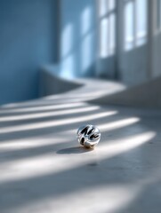 Modern metallic ball with geometric cutouts on a sunlit surface, abstract object in minimalist space