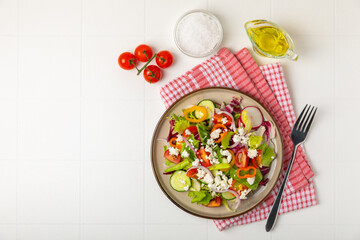 Cucumber salad on a wooden background.Homemade salad with fresh vegetables, cucumber, tomato, sweet pepper and lettuce in a plate.Vegetarian spring salad.Vegetarian diet.Healthy eating.Space for text