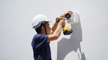A technician installs a CCTV camera on the facade of a residential building
