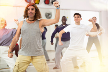 Emotional adult man attending group choreography class, learning modern dynamic dances..